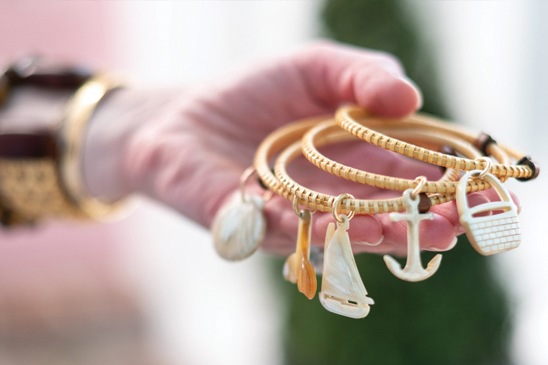 A hand holding bangle bracelets with nautical charms.