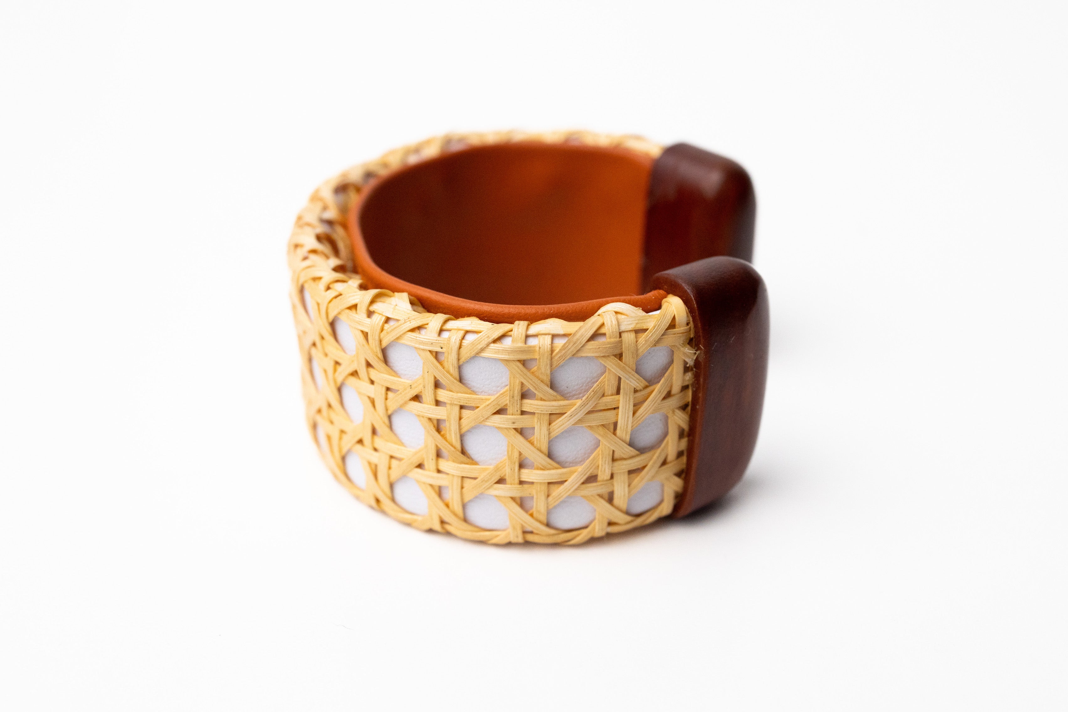 A white cane cuff bracelet with Italian leather base and hand-carved wooden ends, displayed against a white background.