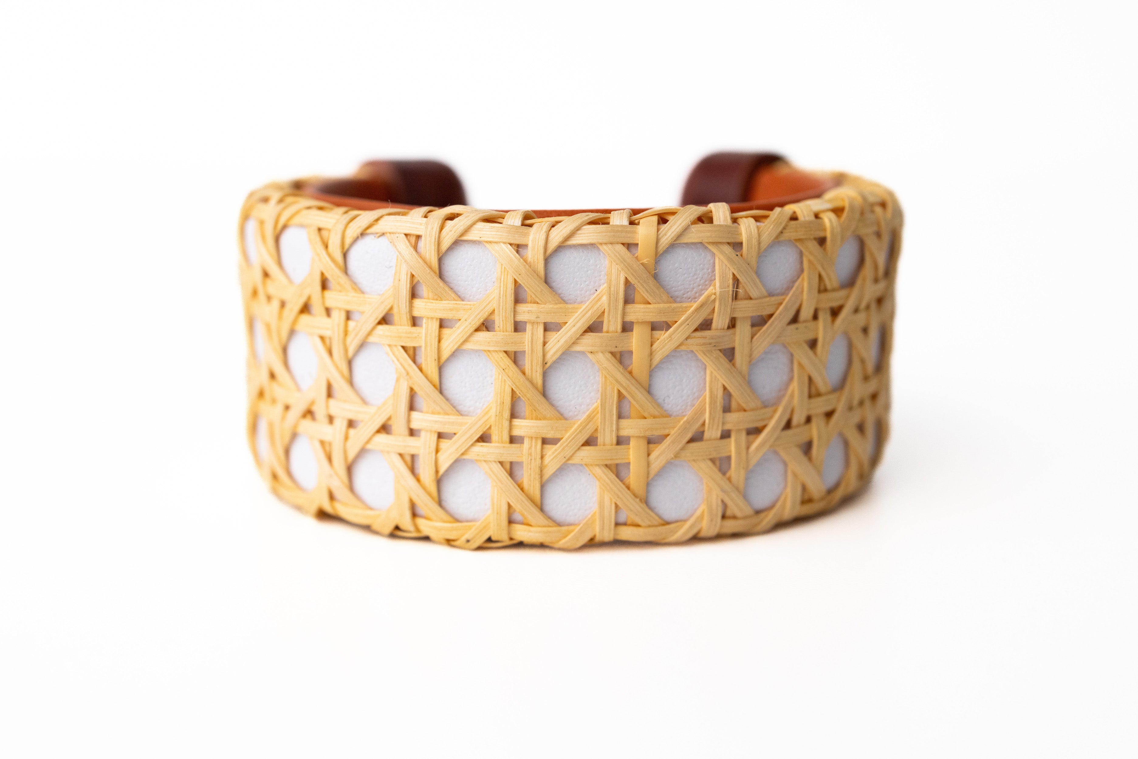 A white cane cuff bracelet with Italian leather base and hand-carved wooden ends, displayed against a white background.