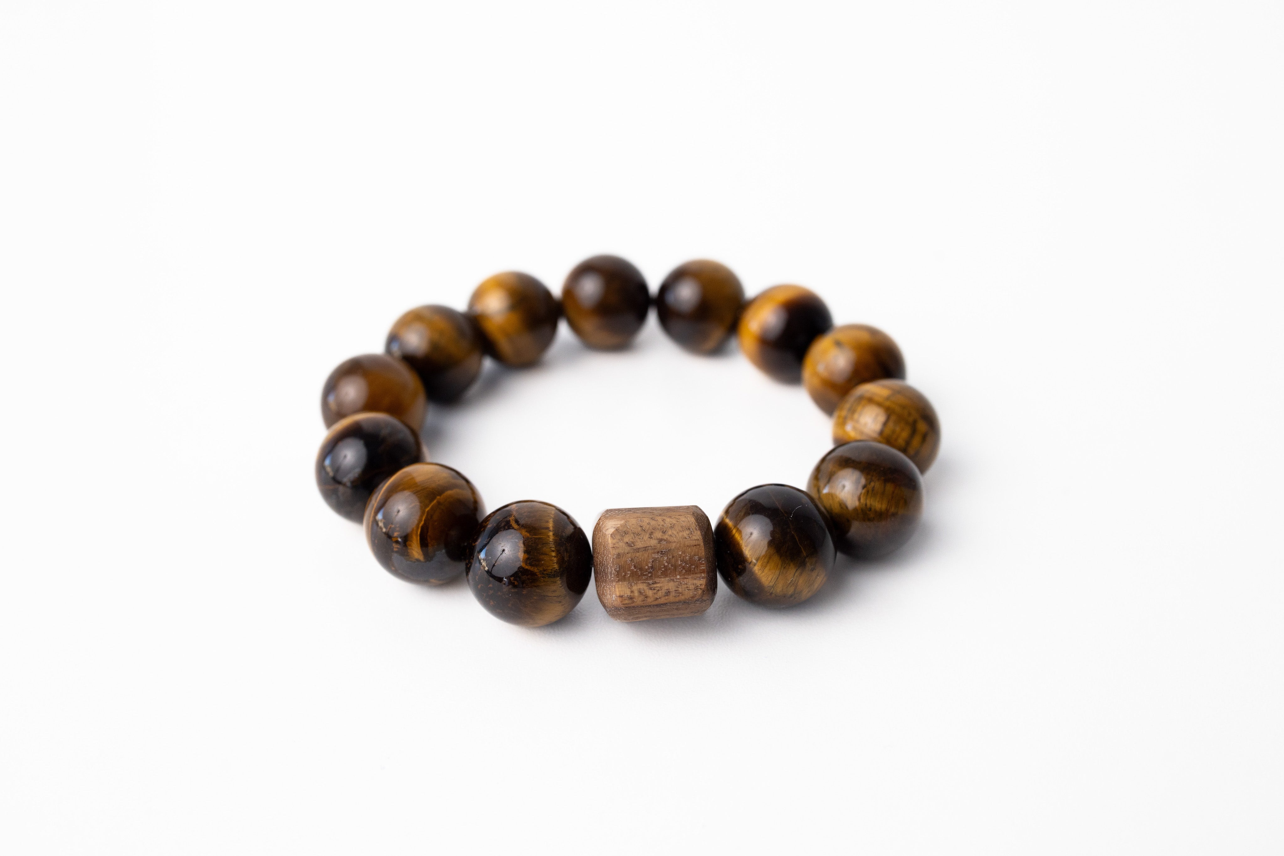 A Tiger's Eye stone beaded bracelet with a woven wood cane bracelet closure, on a white background.