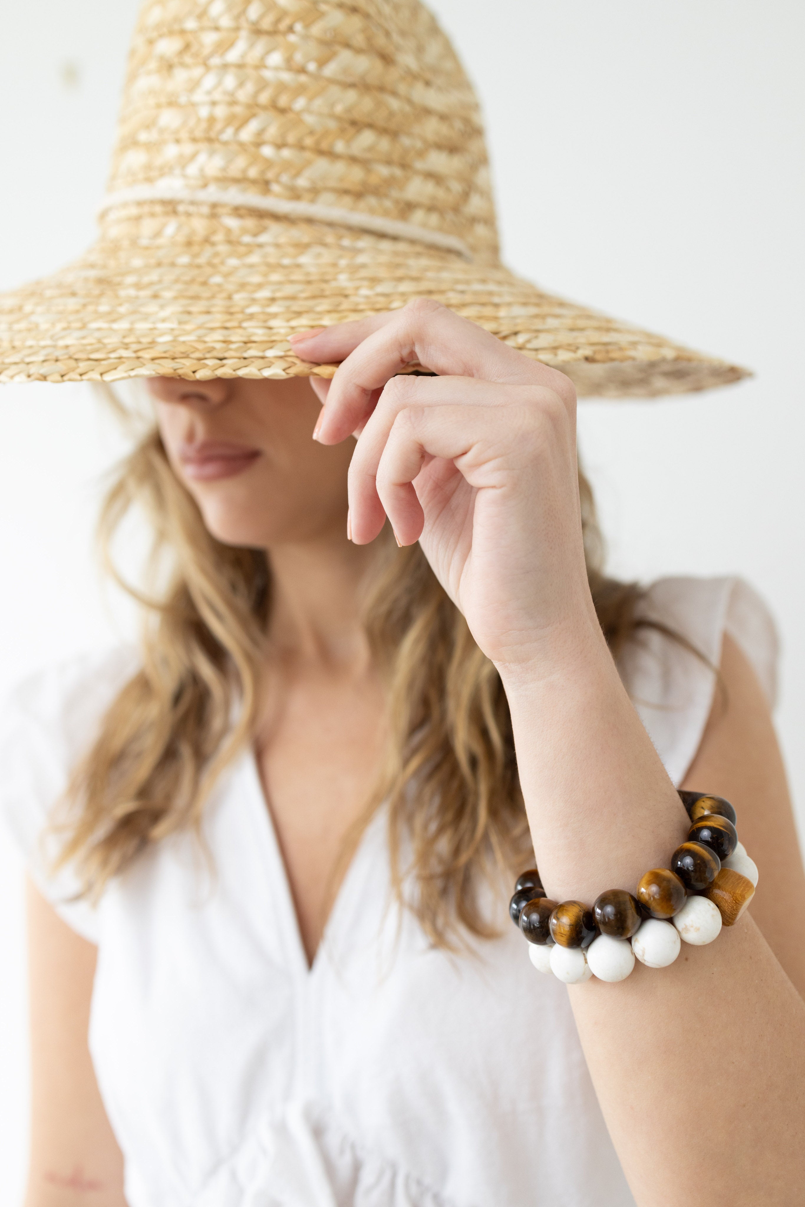 A woman in a sunhat wearing two beaded bracelets around her wrist.