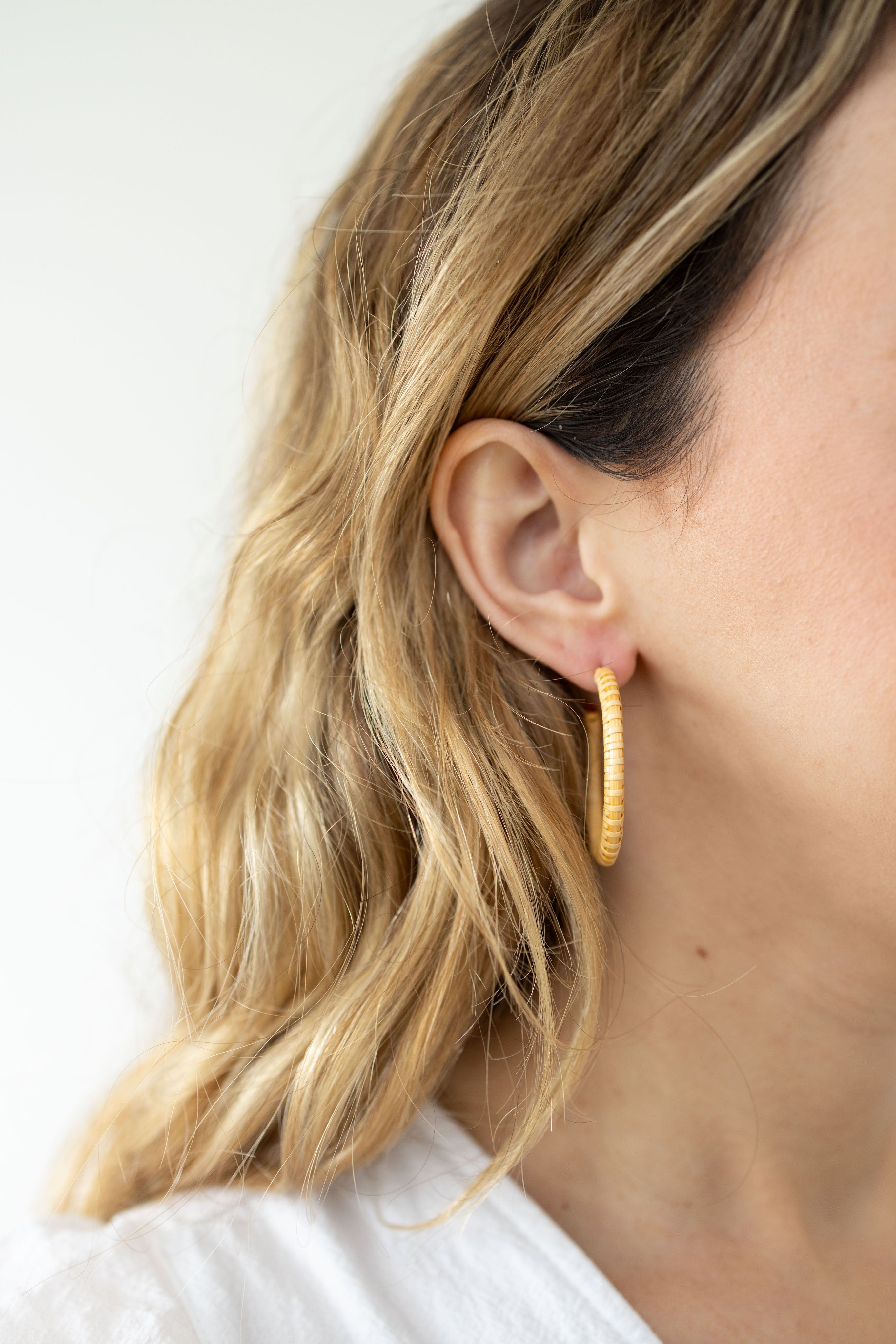 A woman with blonde hair waring nautical hoop earrings in her right ear.