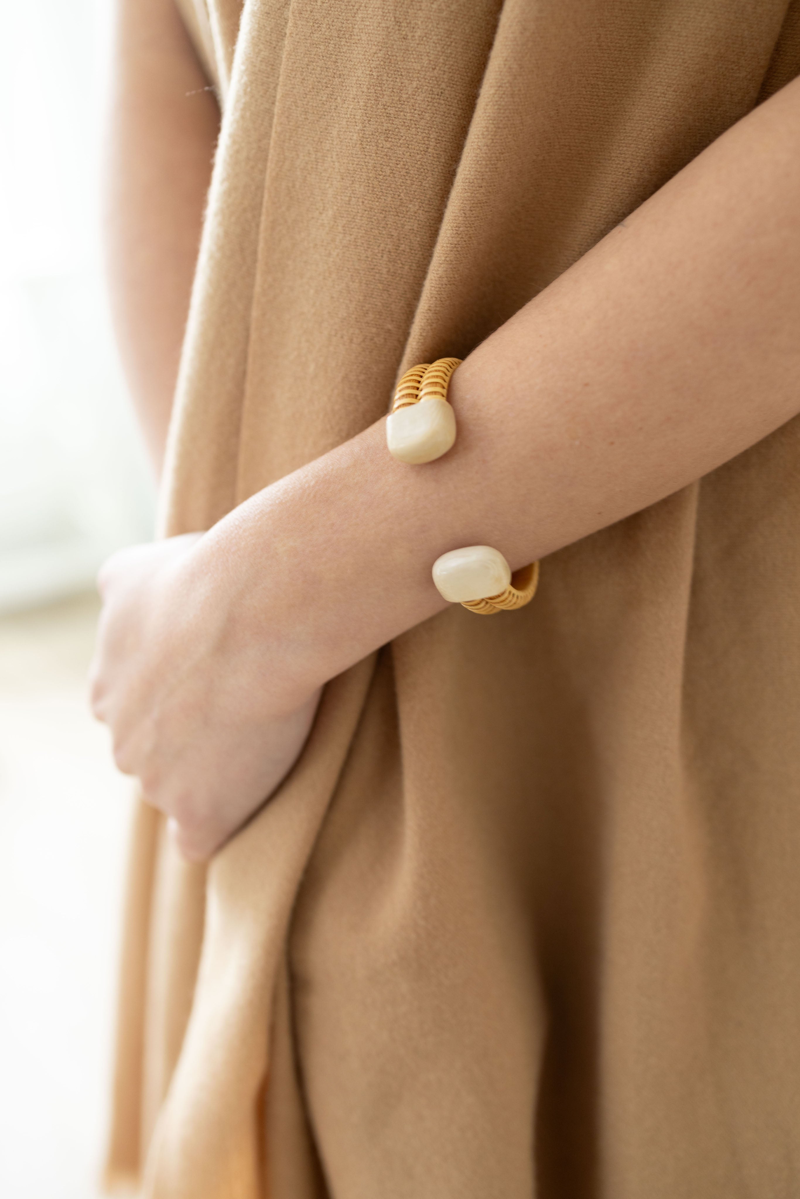 A woman's arm with a handmade bracelet cuff with white caps around her wrist.