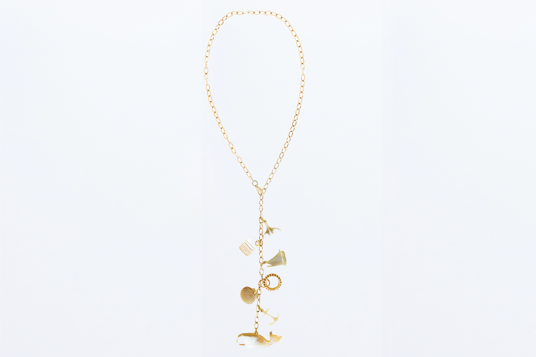 A long Y style necklace with a gold-linked chain and six nautical charms made from buffalo horn.