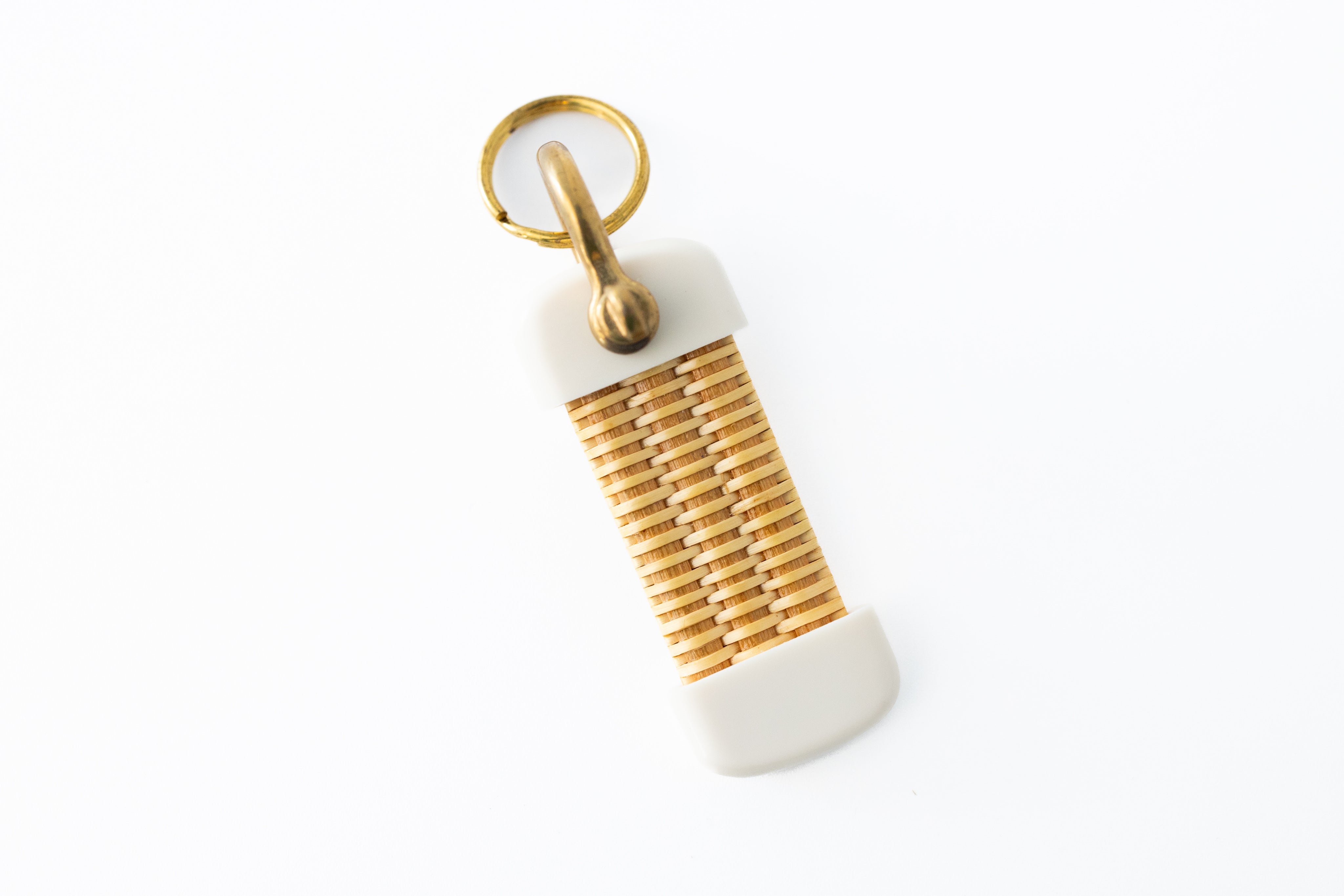 A white and beige Nantucket basket keychain with a brass shackle, displayed against a white background.