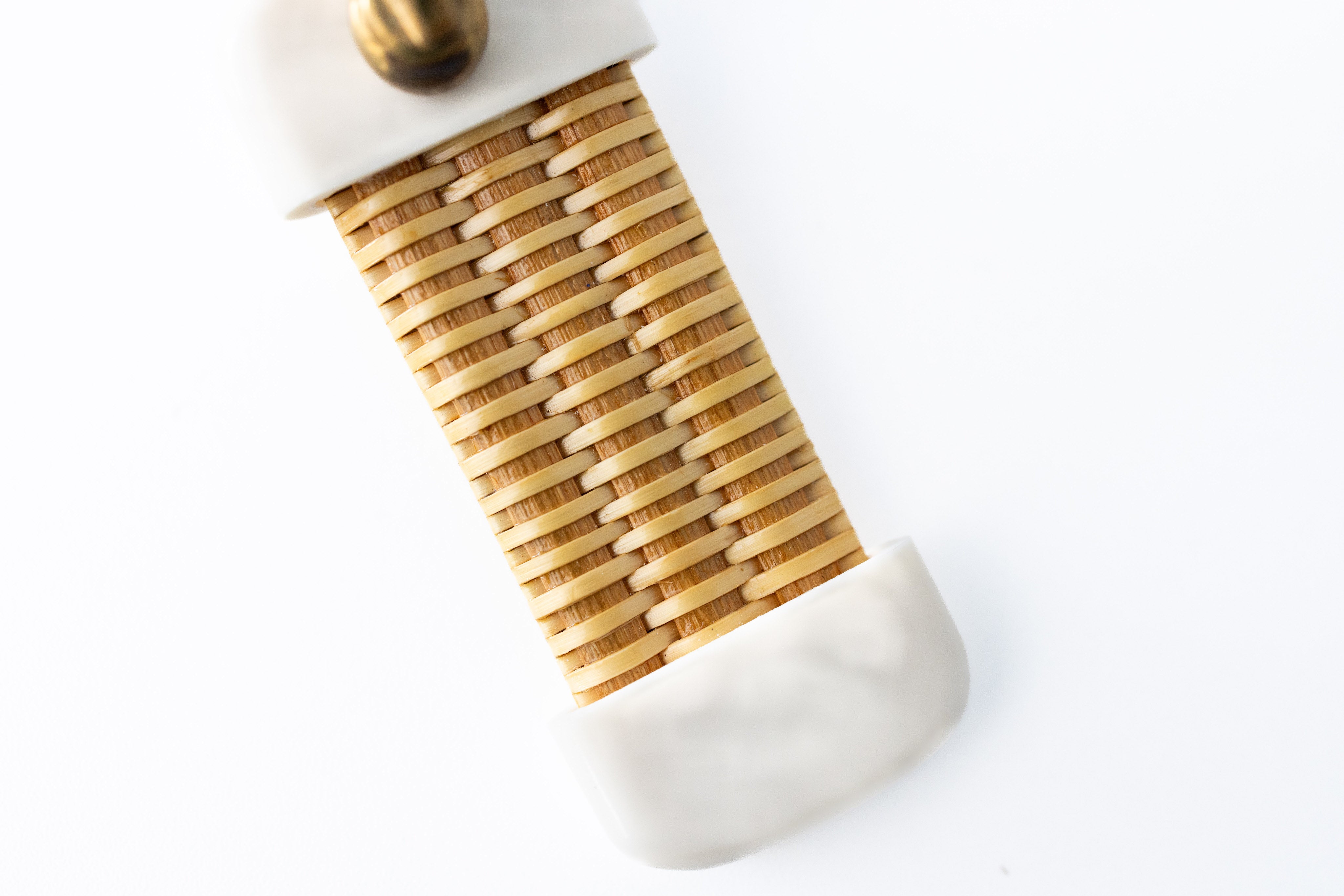A close up of a white and beige Nantucket basket keychain displayed against a white background.