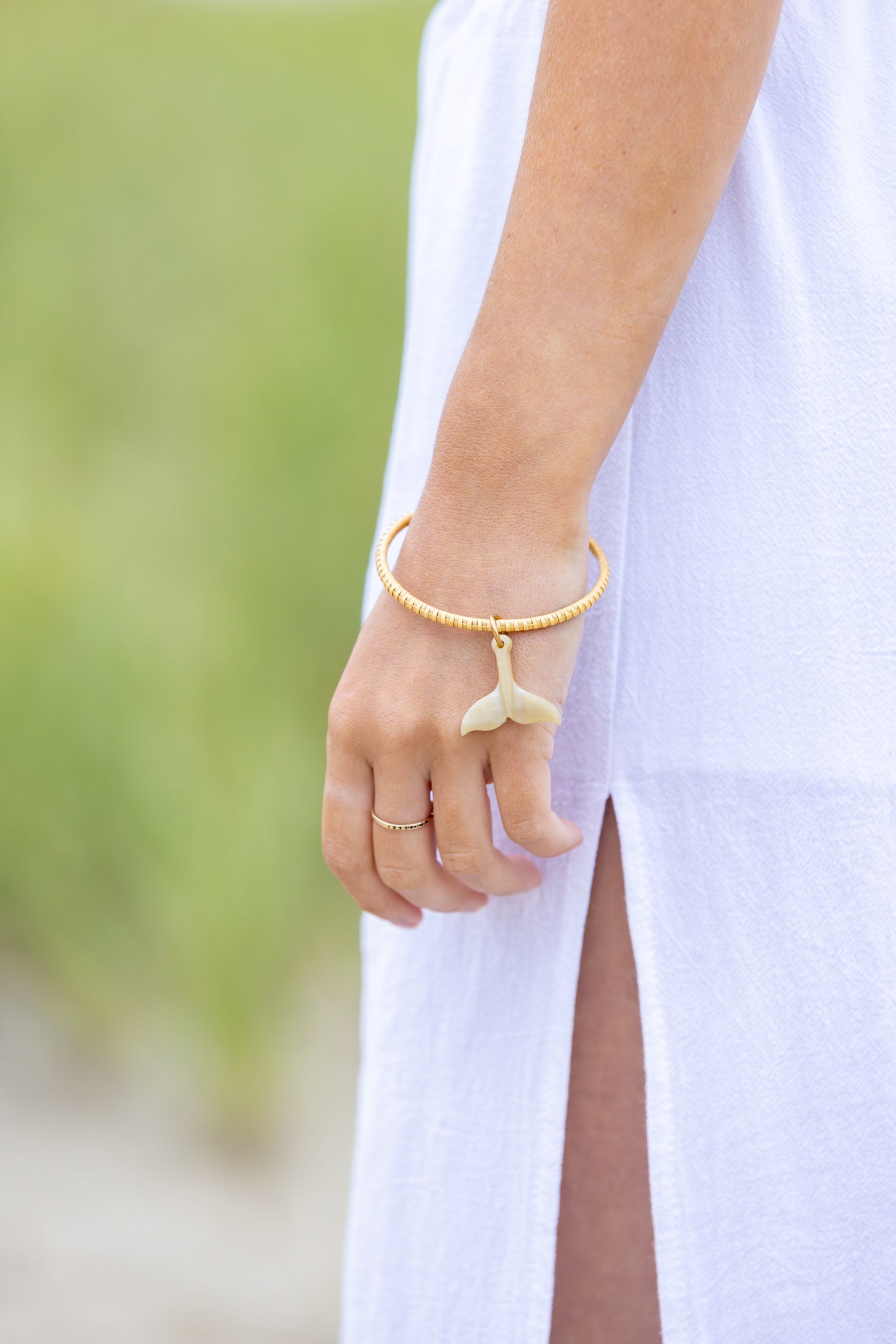 Close up of arm wearing bangle with whale tail charm.