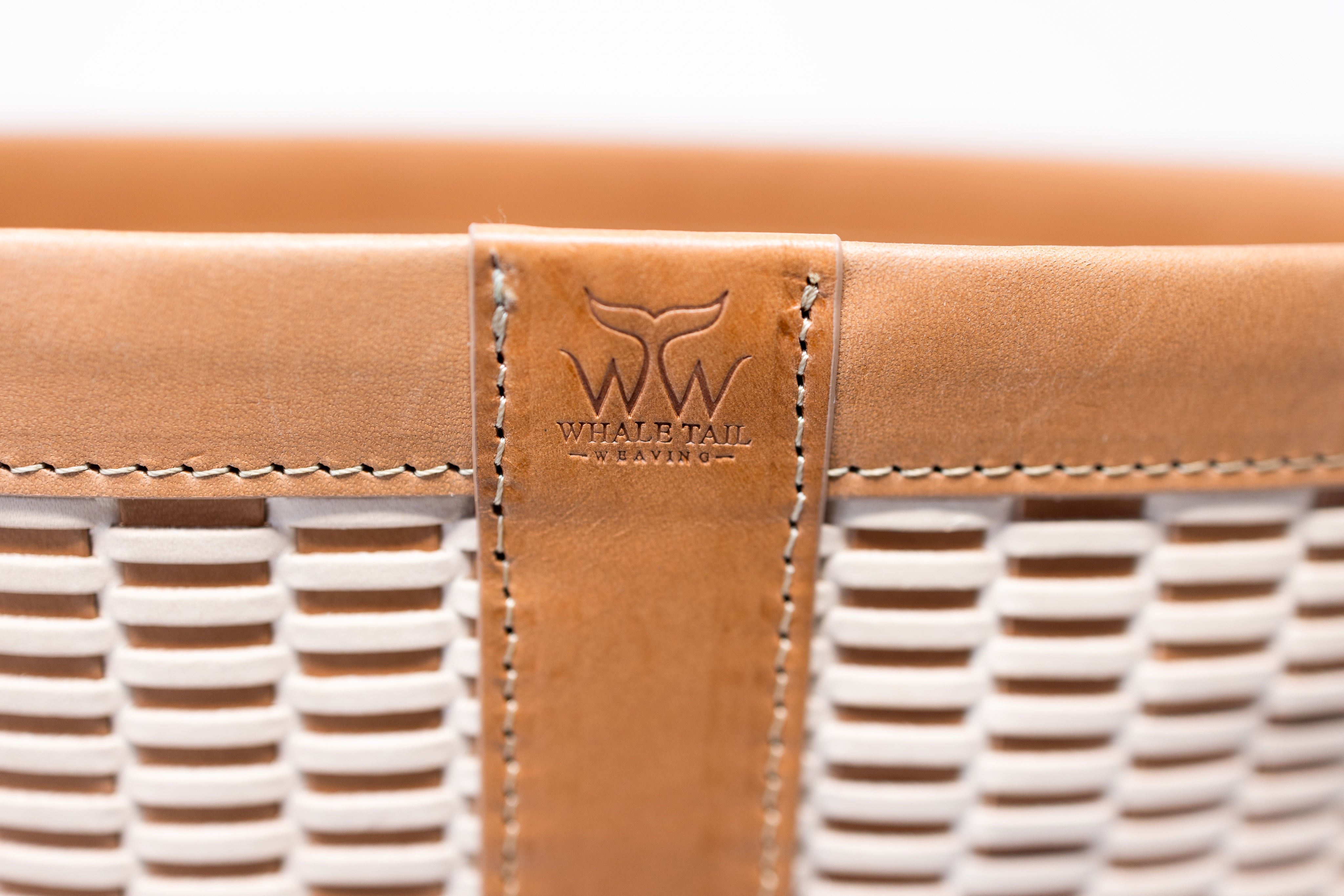 A close up of the Whale Tail Weaving logo engraved on the brown leather.