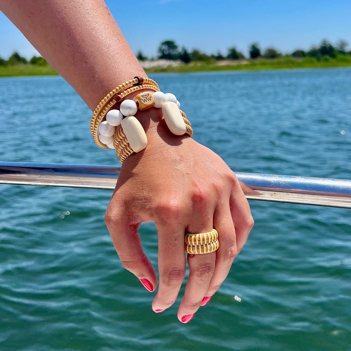 A woman's hand resting on a railing with Nantucket Jewelry on.