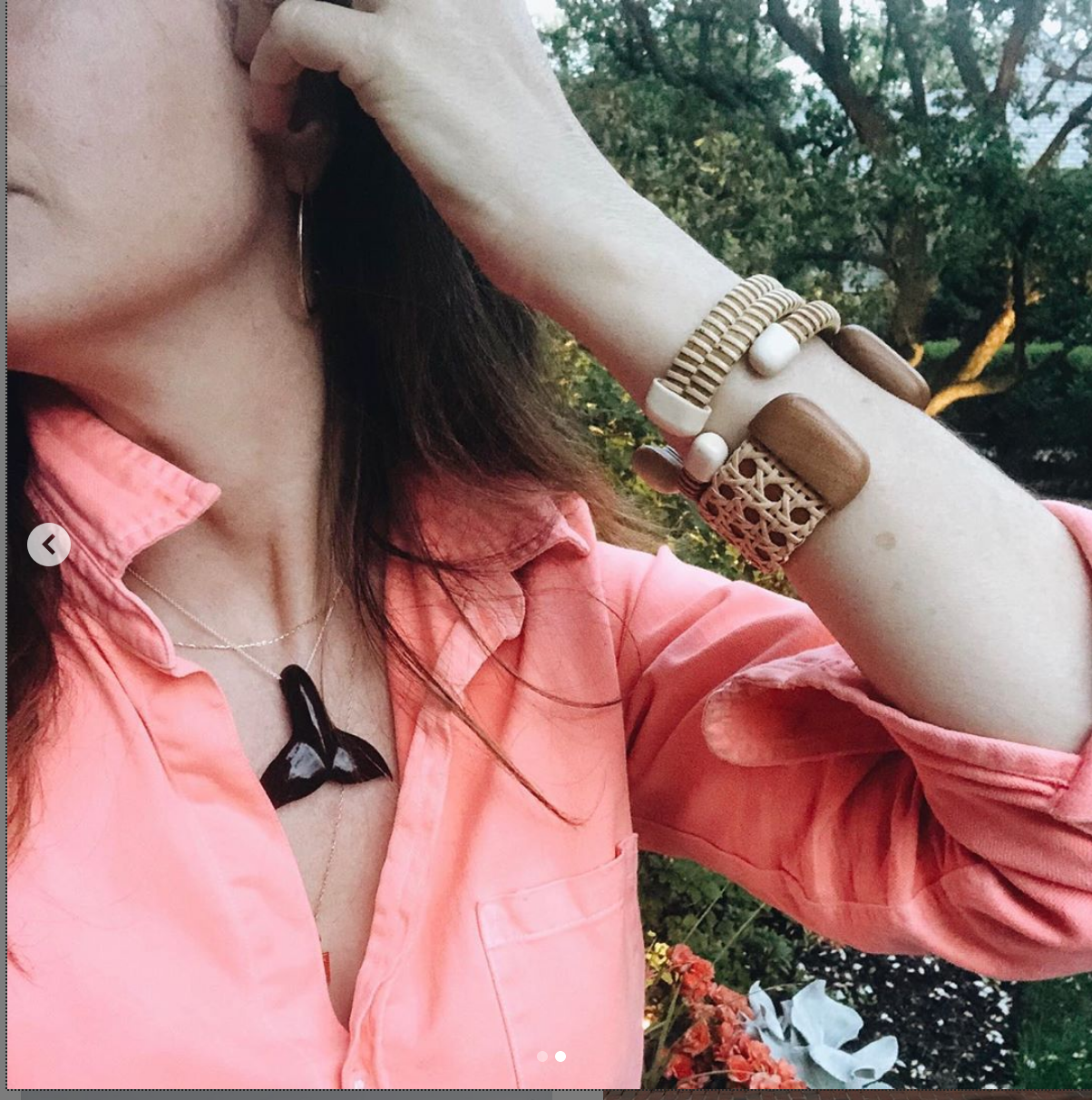 A woman wearing a whale tail pendant and Nantucket bracelets on her arm.